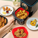 Person using an air fryer with plates of food 